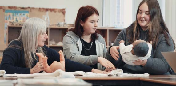 Teacher and students learning how to change a nappy in education class