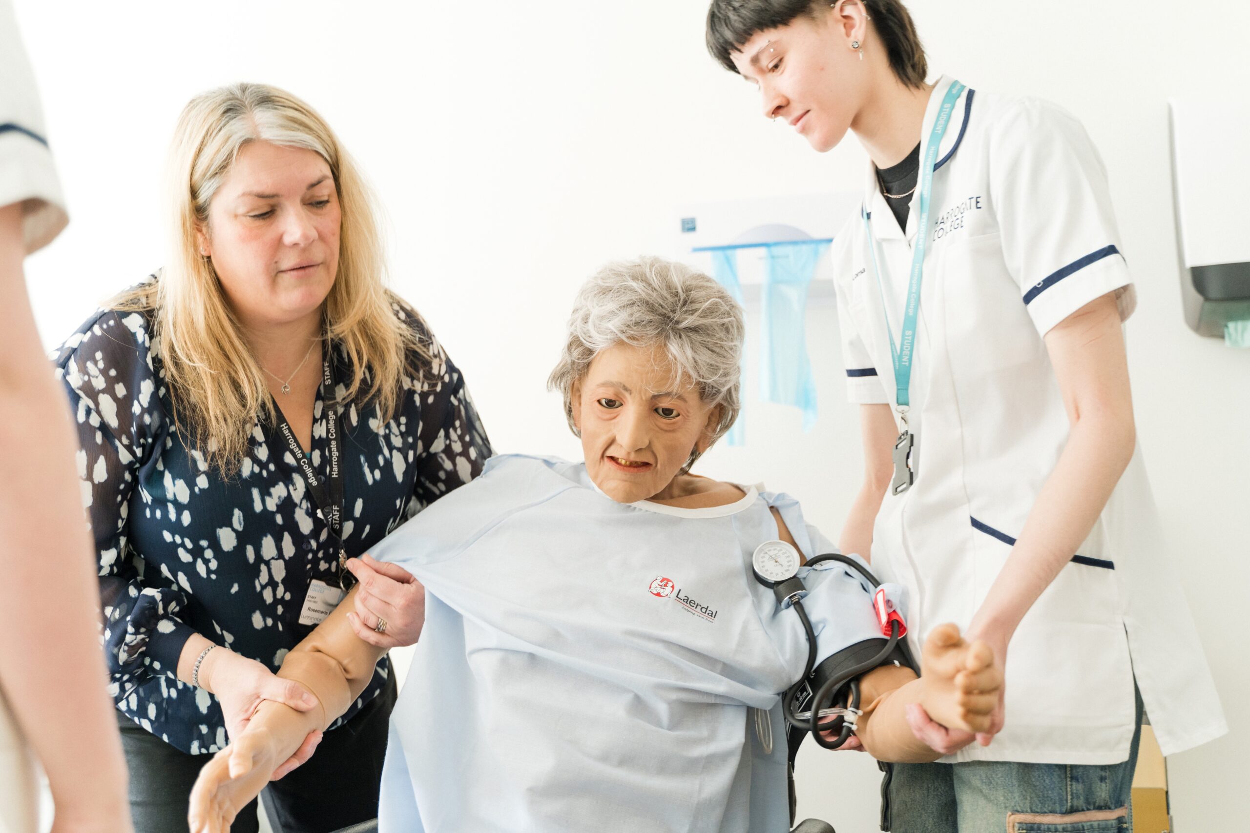 Students using a training manikin to learn how to assist a patient into a wheelchair