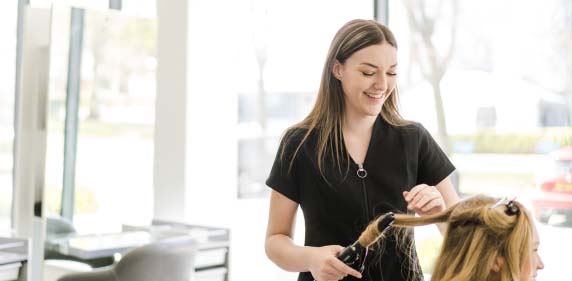 Student learning how to curl a client's hair in the hairdressing training salon at Harrogate College